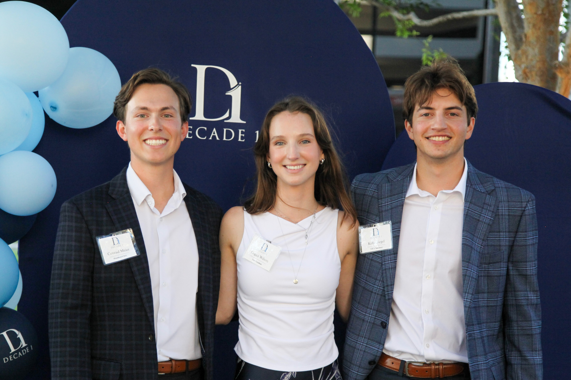 Decade 1 founding members in front of the Decade 1 event backdrop